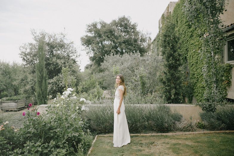 Elegant white dress captured in a lush garden setting with ivy-covered walls.