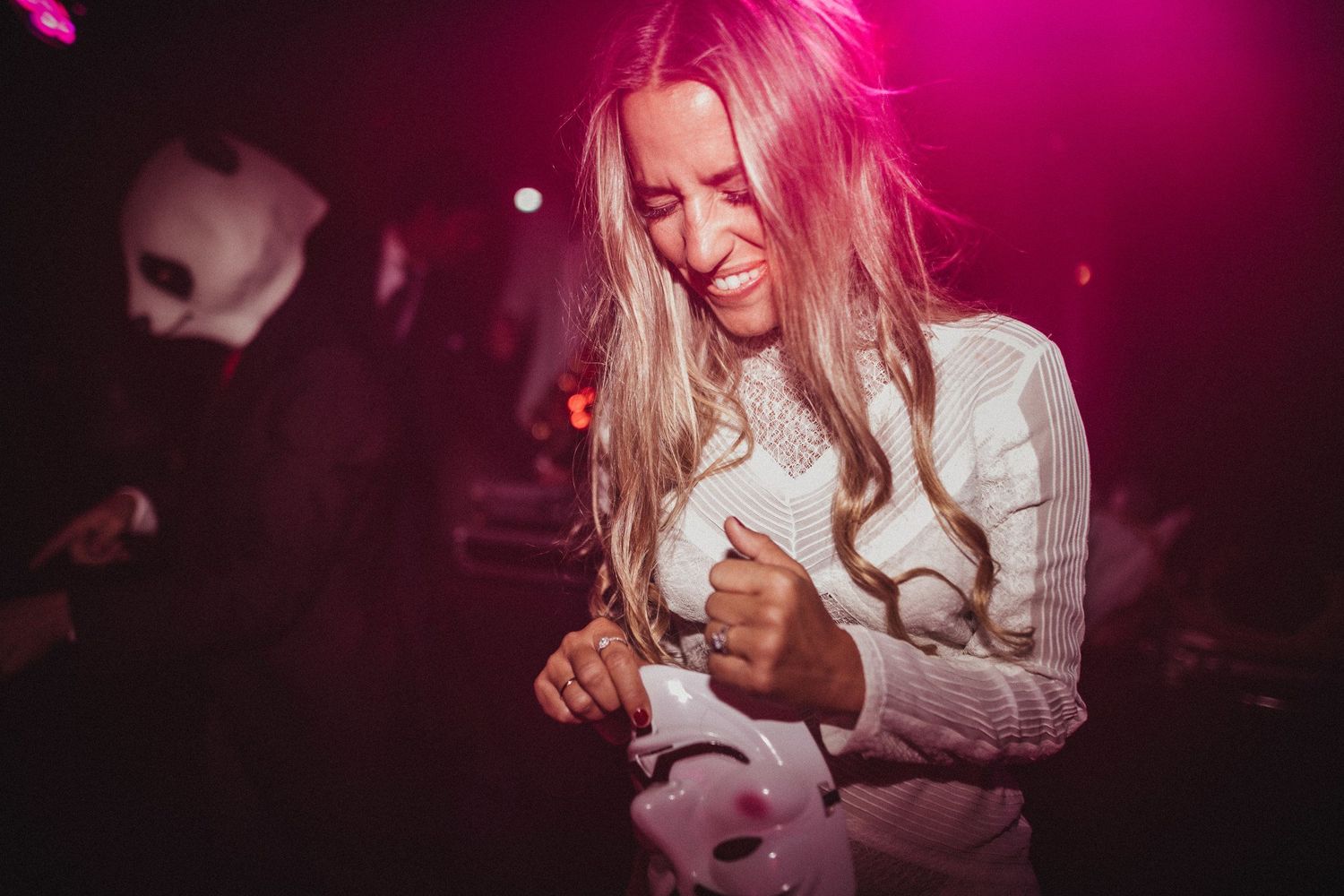 Joy-filled dance moment at wedding reception with vibrant pink lighting.