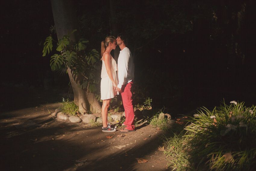 A couple shares an intimate moment on a dimly lit garden path at night.