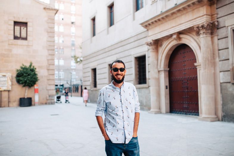 Casual portrait in front of historic stone architecture with arched doorways.