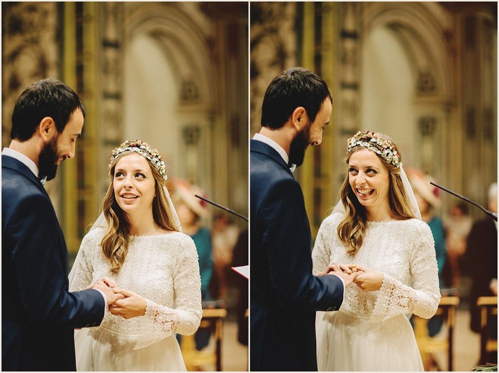 A couple exchanges rings during their wedding ceremony in a grand cathedral with arched architecture.