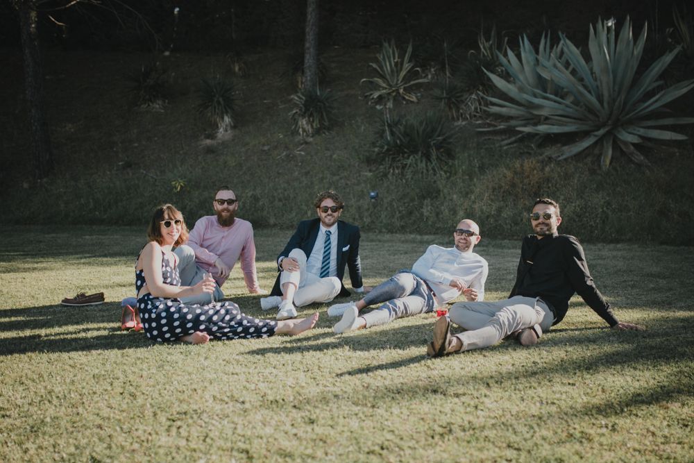 Small group relaxing on grass during outdoor garden party or reception.