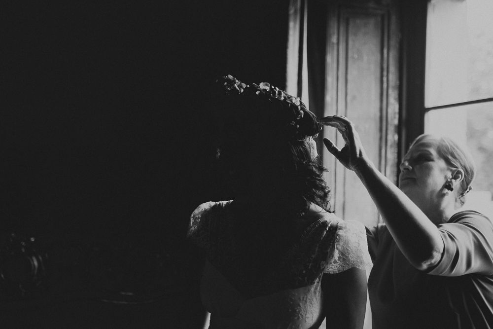 A dramatic black and white photo showing someone getting their hair styled in front of a window.