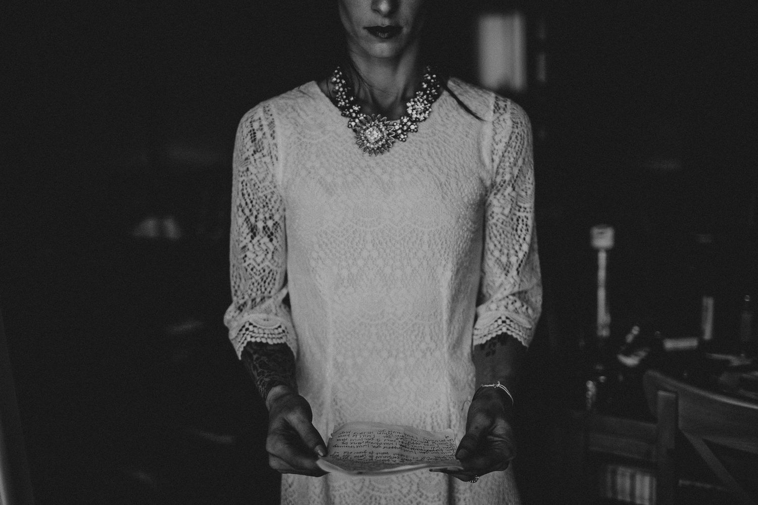 Black and white photo showing delicate lace top with statement necklace detail.