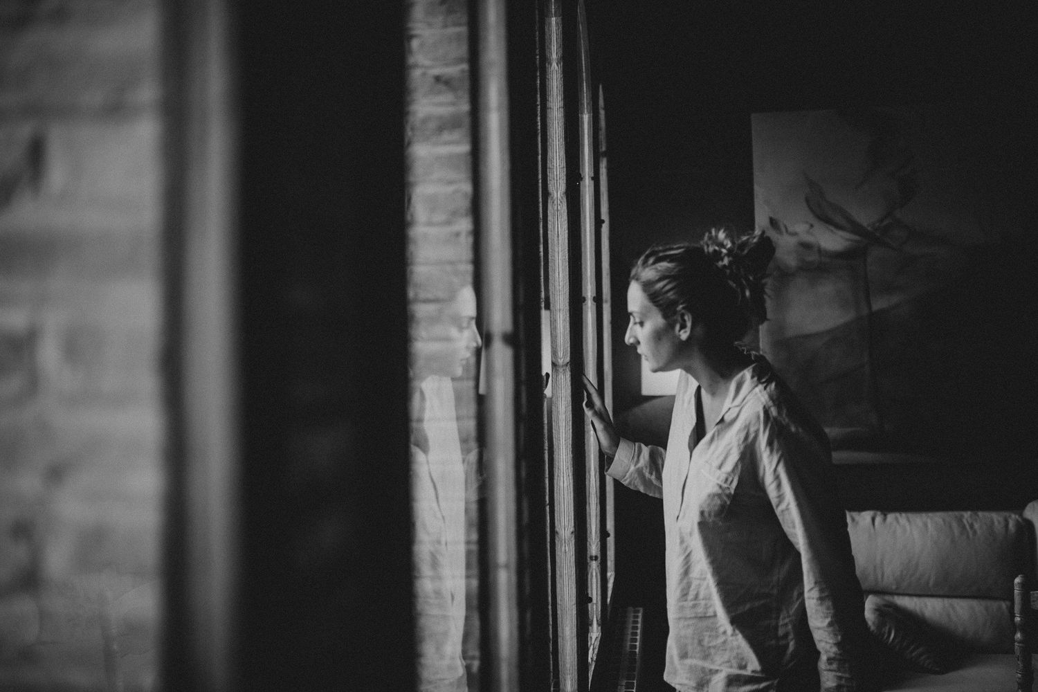 Black and white photo of figure gazing through ornate window.