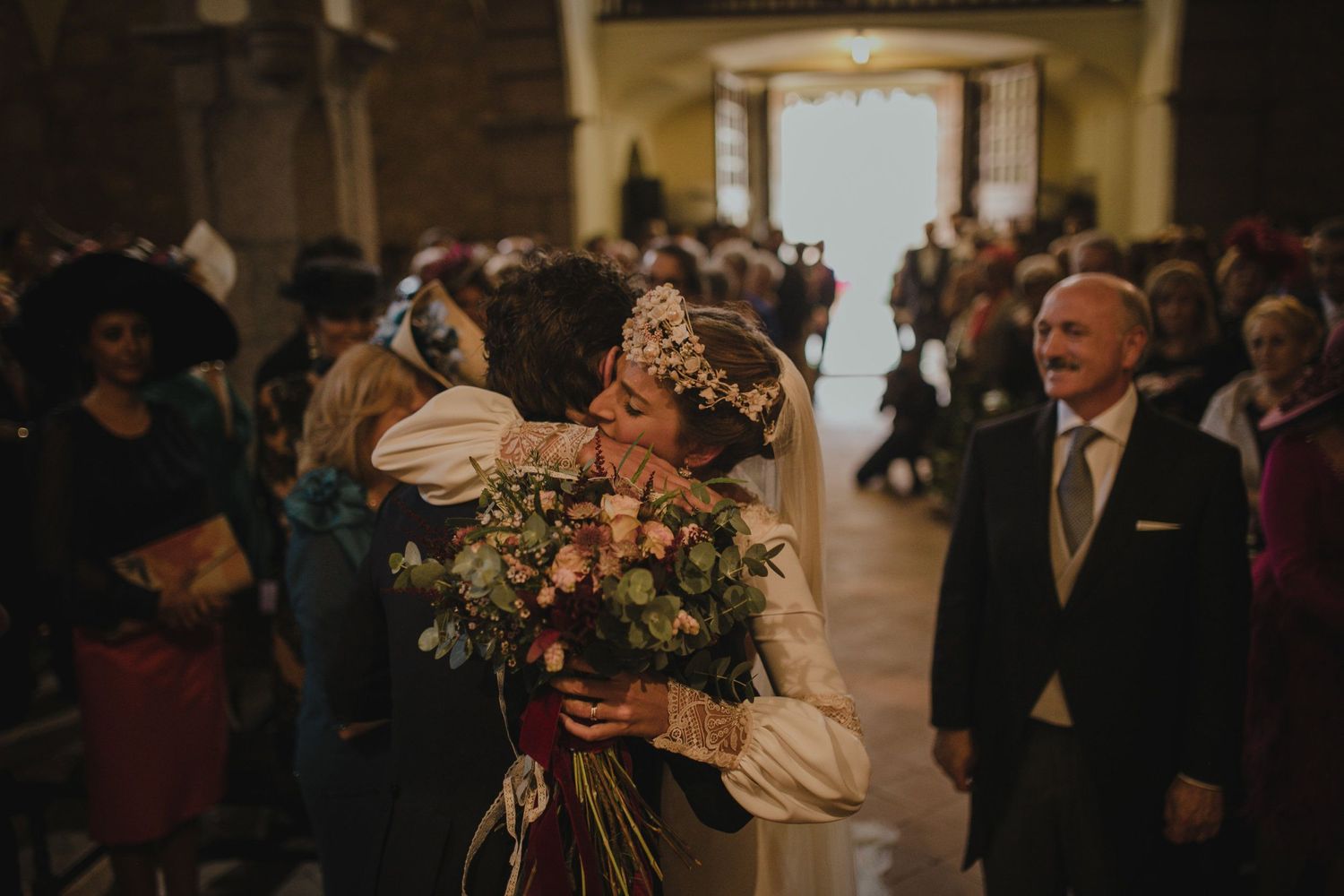 Wedding celebration inside historic stone church with guests and floral decorations.