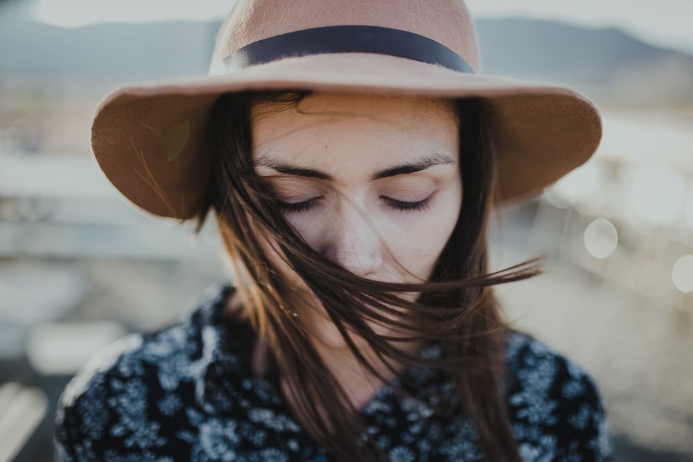 A stylish brown hat casts shadows on a wind-swept desert scene.