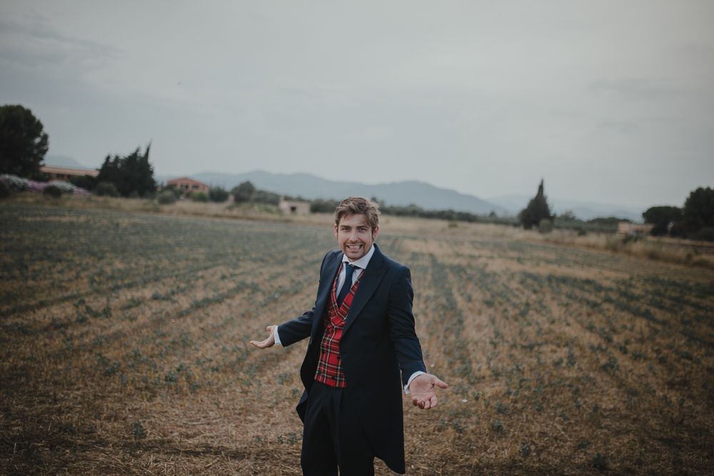 Person in formal attire gesturing while standing in an open field.