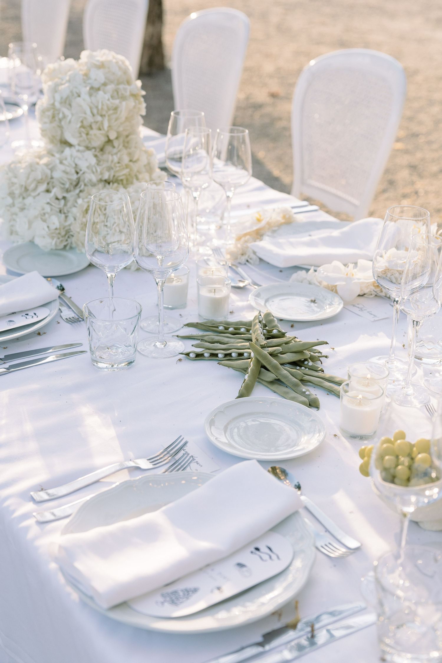 Elegant white wedding reception table setting with floral centerpieces and crystal glassware.