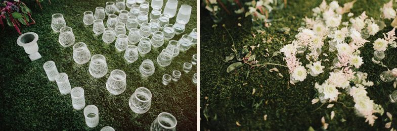 Glass drinking vessels arranged on grass near white floral decorations.