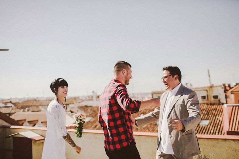 Three people share a lighthearted moment during a rooftop ceremony.