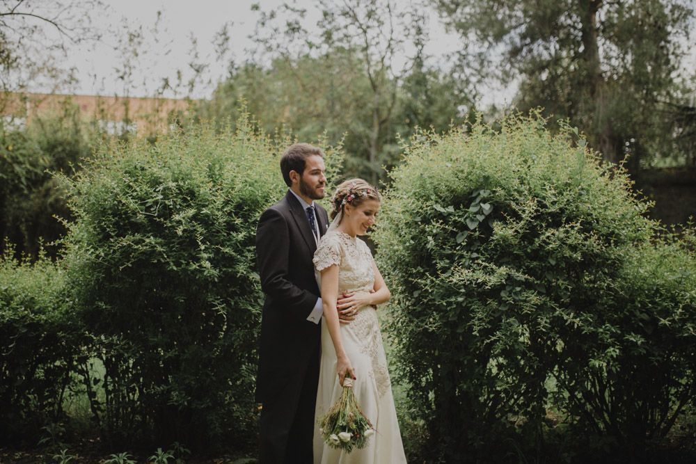 Couple standing together in a lush garden setting during their wedding photoshoot.
