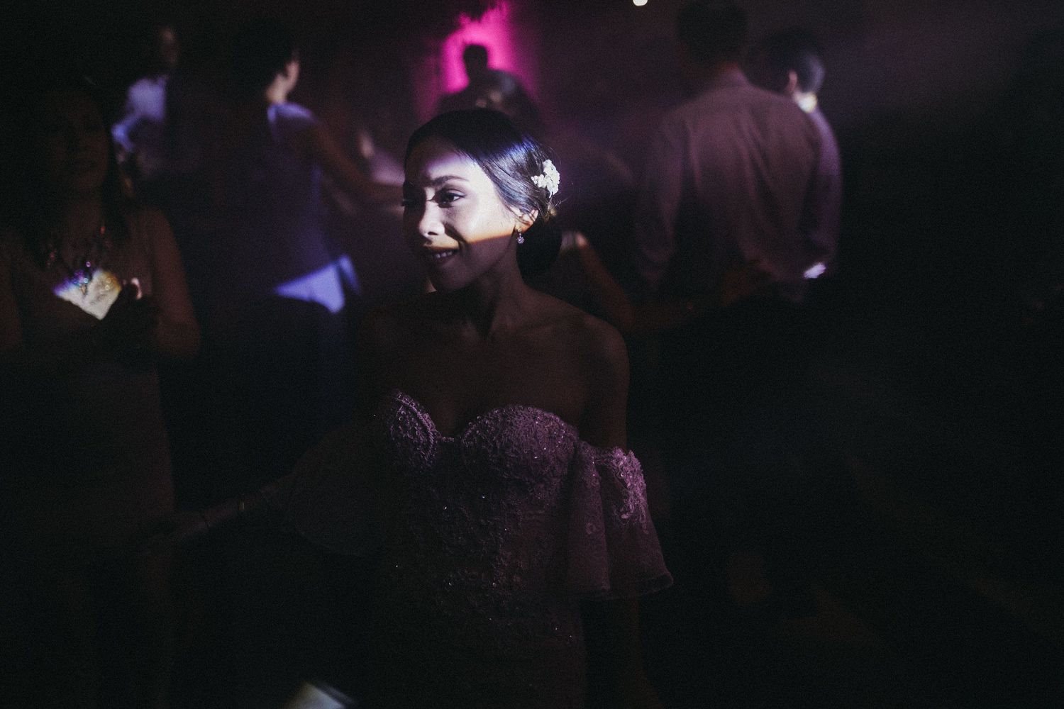Dreamy dance scene at reception with moody purple lighting and formal attire.