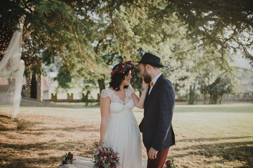 An intimate moment captured during an outdoor wedding under a large tree.