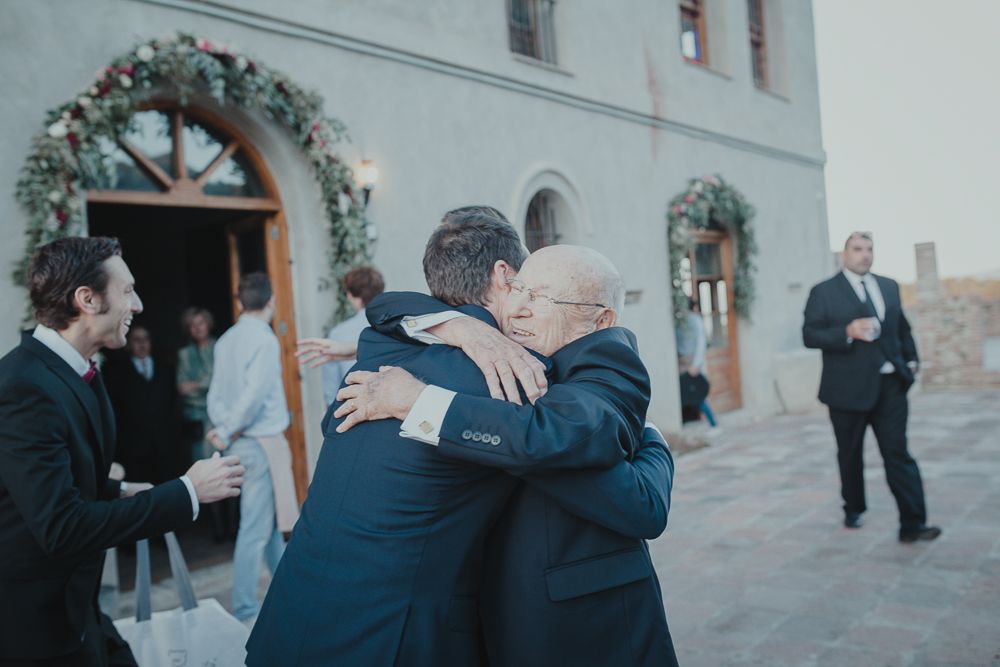 Two people embracing outside a church entrance decorated with floral garlands.