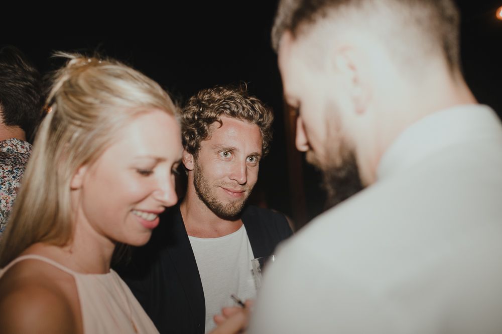 Party guests engage in animated conversation at a dimly lit evening social gathering.