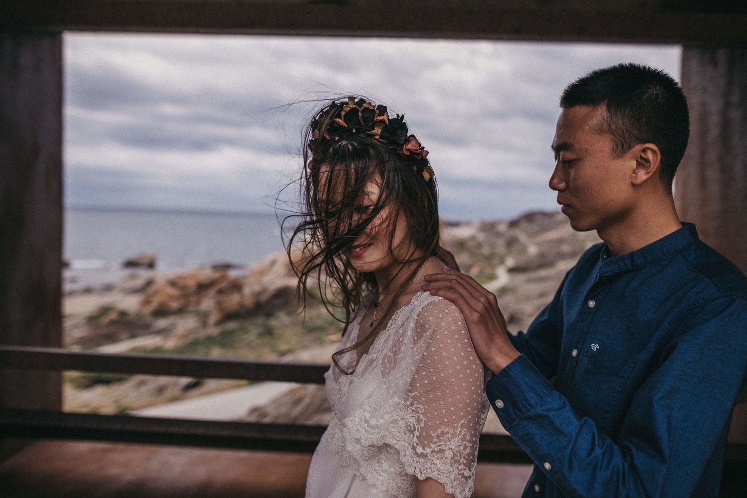 An intimate moment between a couple at a scenic overlook with moody overcast skies.