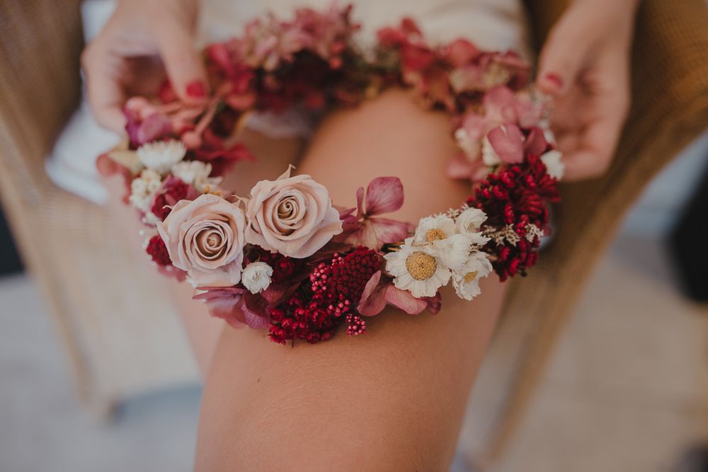Close-up of pink and burgundy floral crown with roses and delicate blooms.