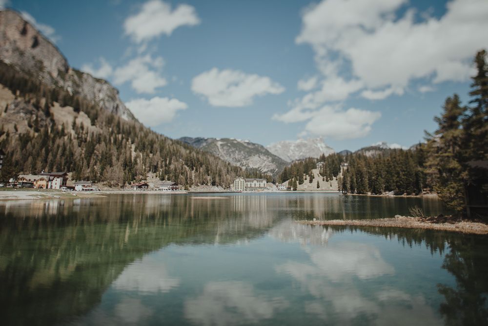 Serene mountain lake reflects surrounding peaks and evergreen forest under blue skies.