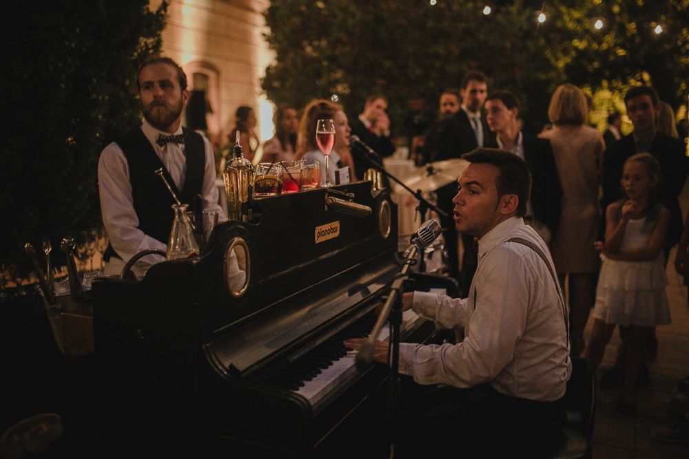 Vintage piano player entertaining guests at an outdoor evening wedding reception.