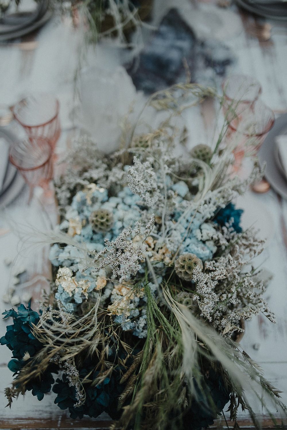 Close-up of dried floral arrangement with delicate white flowers and blue tones on a table setting.
