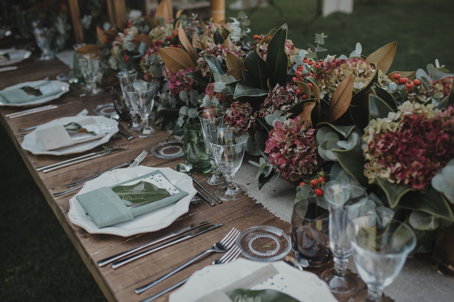 A wedding reception table decorated with pink floral arrangements and elegant place settings.