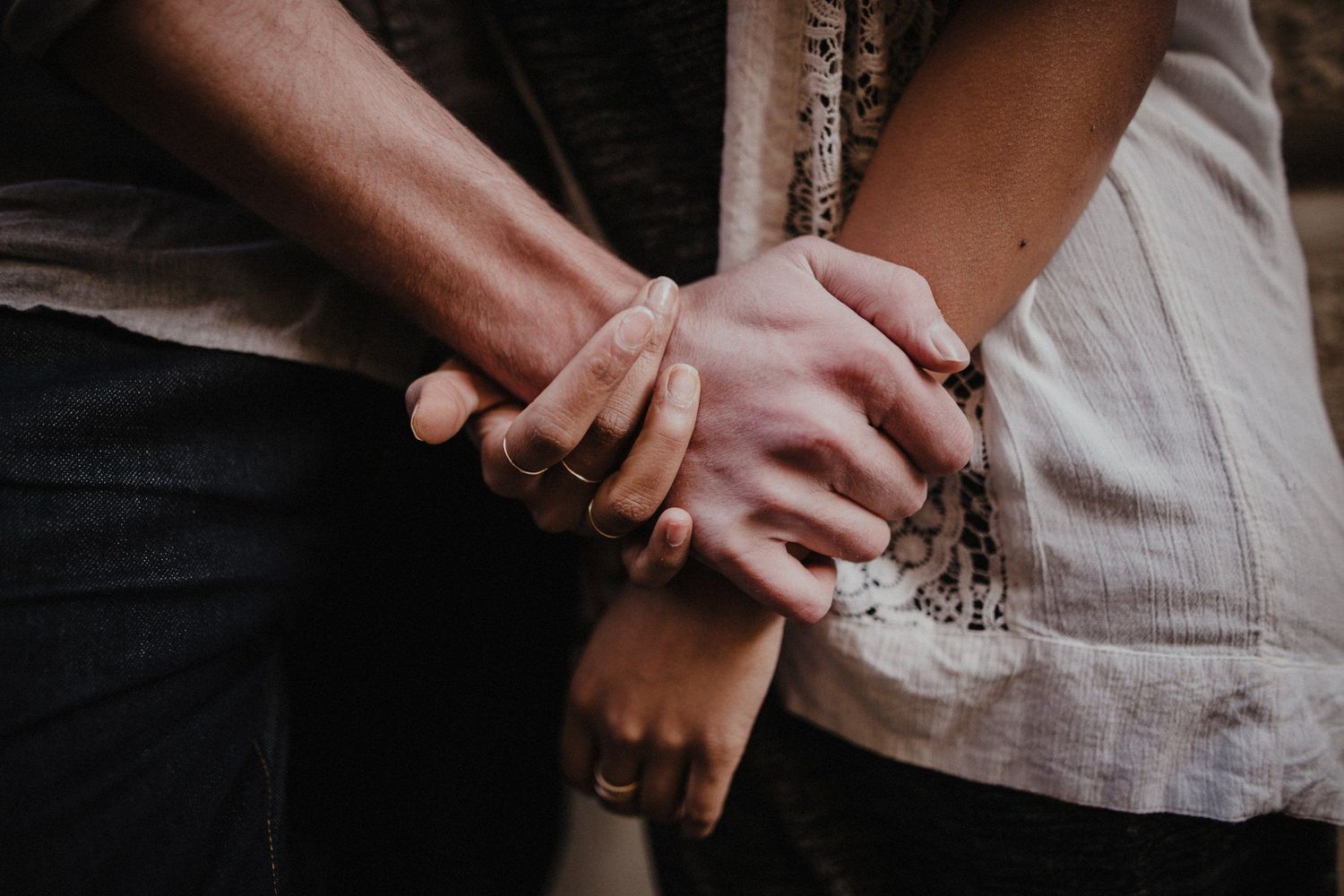 Close-up of intertwined hands showing intimate connection between two people.