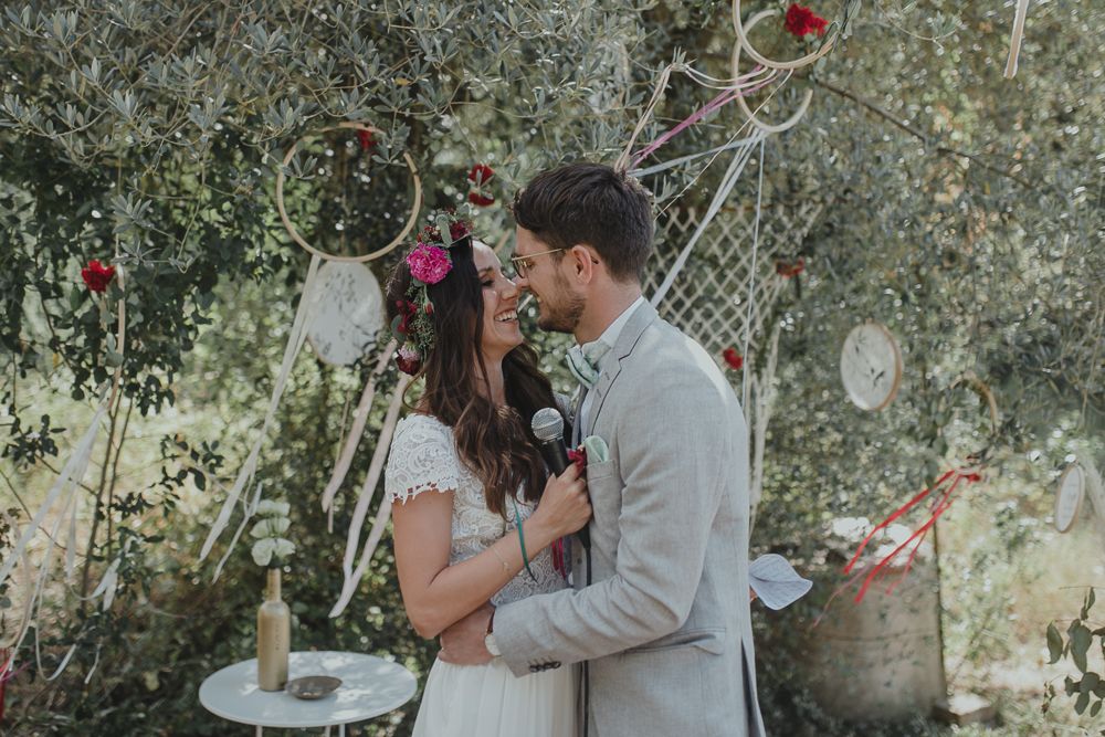 Rustic outdoor wedding ceremony with guests watching from a distance in soft natural lighting.
