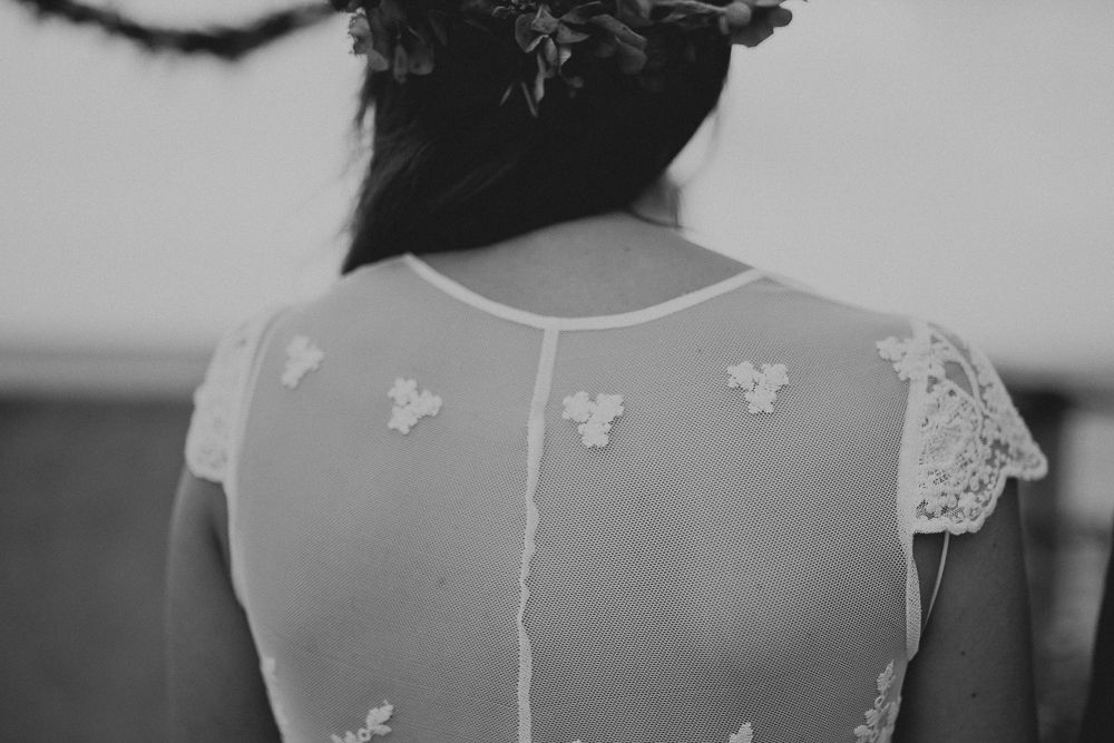 Black and white close-up of delicate lace detail on back of wedding dress.