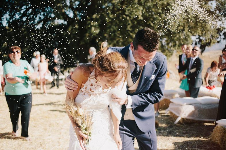 Candid moment of couple dancing and laughing under trees at outdoor wedding reception.