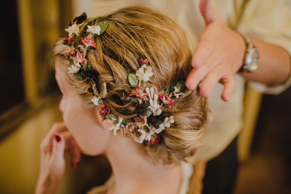 Close-up of an elegant bridal hairstyle adorned with delicate pink flowers and braids.