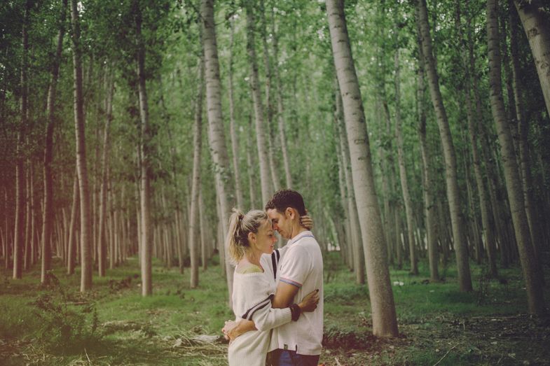 A romantic embrace between a couple in a dreamy forest setting.