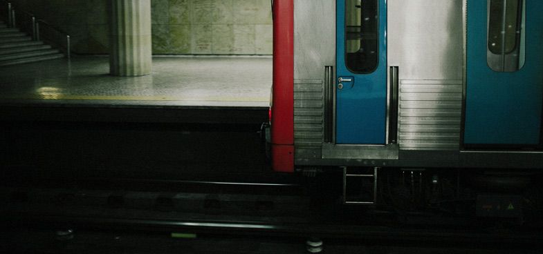 Dark subway platform with colorful doors and steps illuminated by ambient lighting.