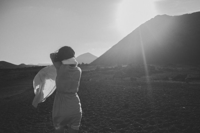 Silhouette of a person looking at mountains during golden hour with sun flare.