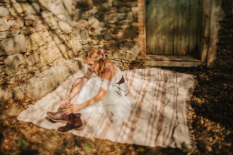 Wedding dress spread out on blanket against rustic stone wall backdrop.