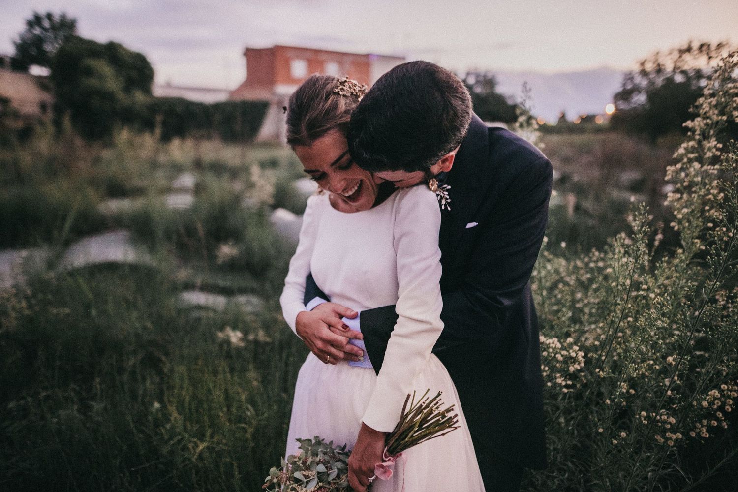 An intimate wedding moment shared between a couple in a rustic outdoor setting at sunset.