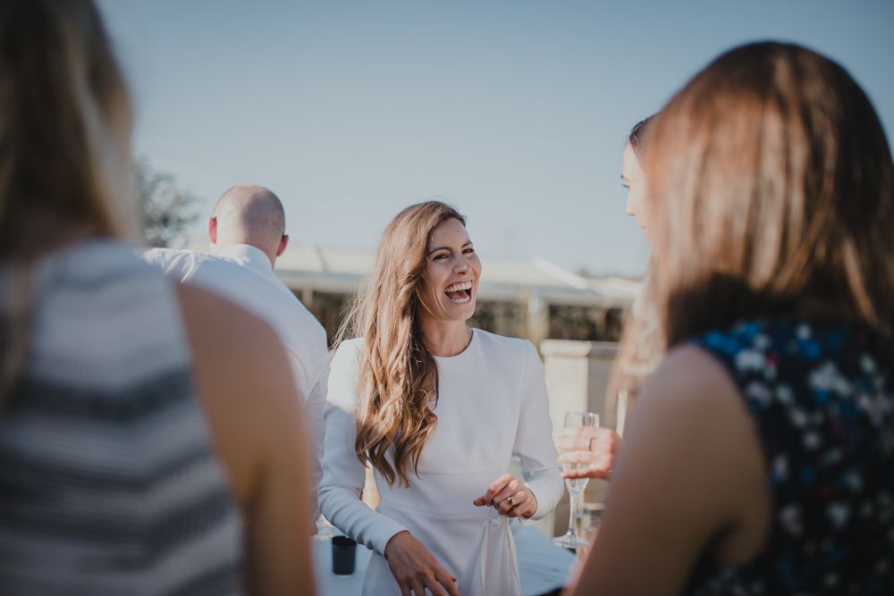 A candid moment of laughter at an outdoor social gathering as friends chat and enjoy drinks.