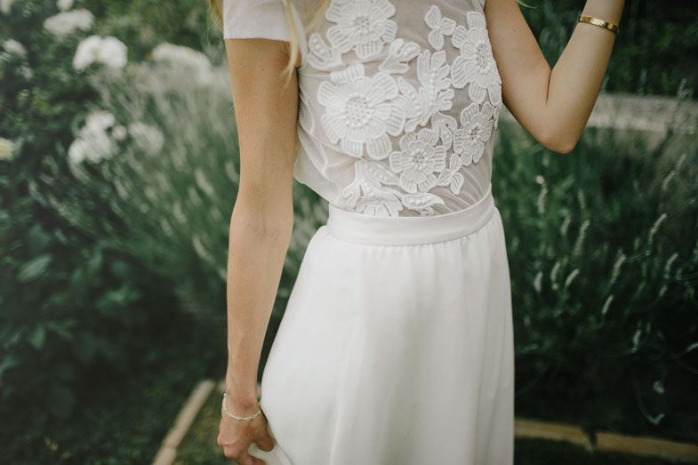Close-up detail of delicate lace bodice and flowing white wedding dress fabric.