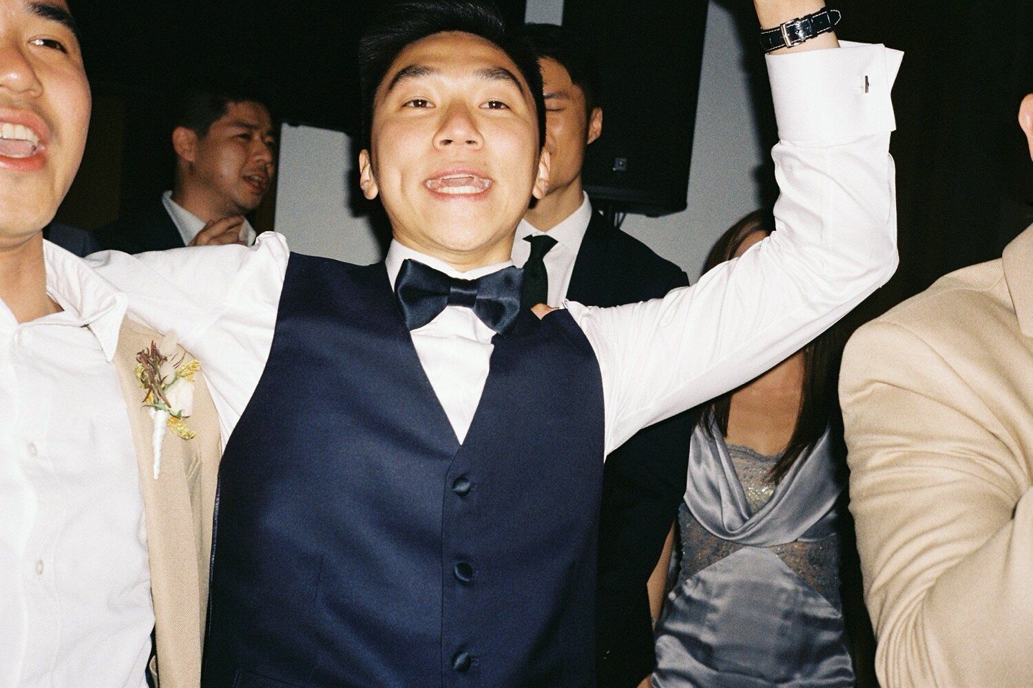 Wedding guest in bow tie celebrating joyfully at reception party.