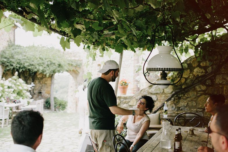 People gathered under a vine-covered pergola during an outdoor meal.