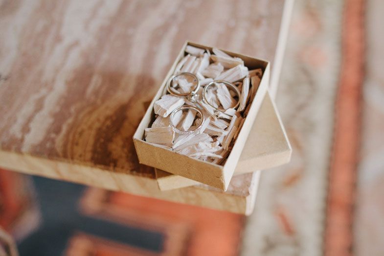 A vintage wooden box filled with cream-colored packing material sits on a wooden surface.
