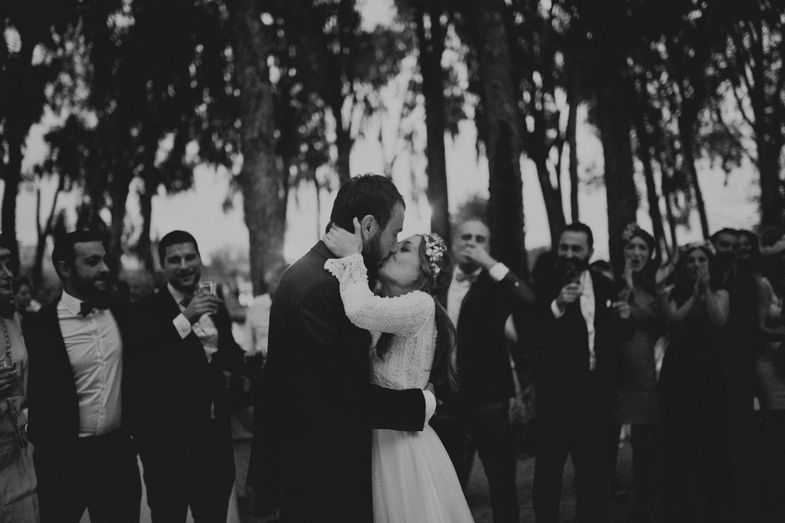 Wedding celebration in a wooded outdoor setting with guests surrounding the couple.