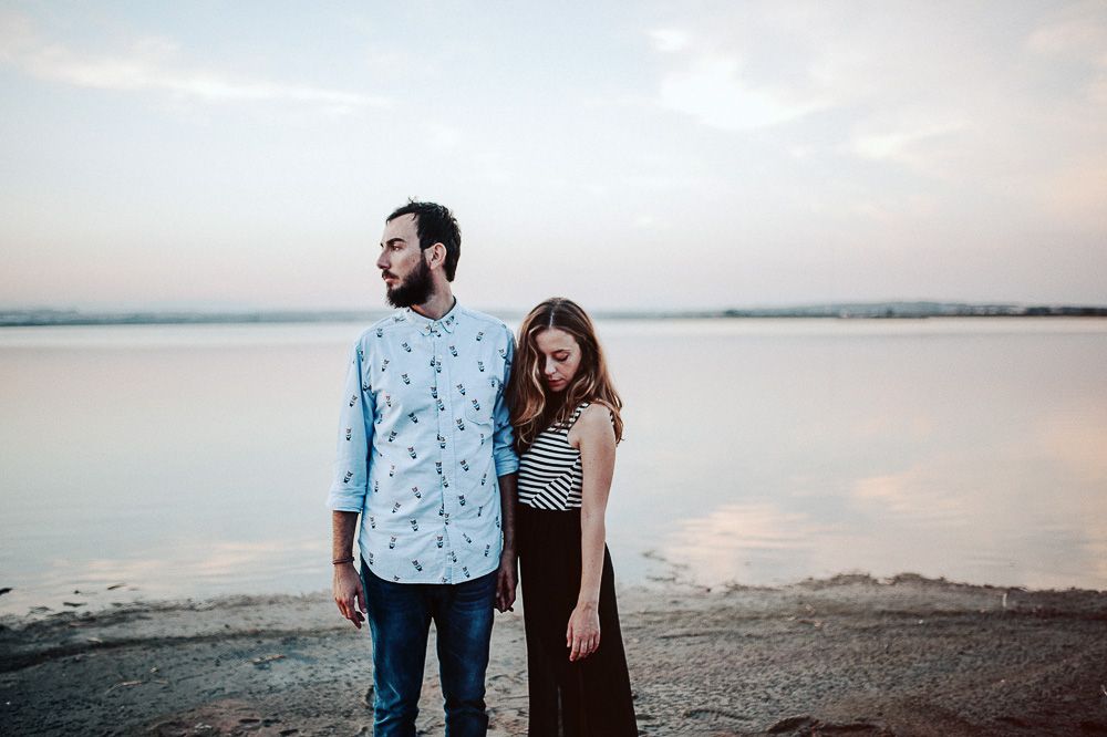 Couple standing side by side on beach during golden hour.