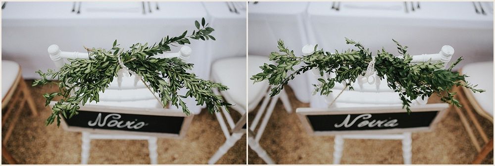 Rustic wedding decor featuring greenery and a sign on a white table.