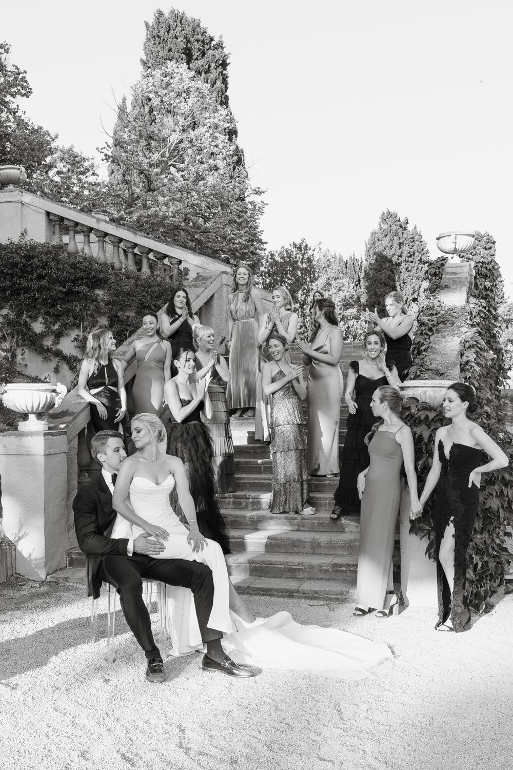 Wedding party poses for fun group photos on outdoor stone steps.