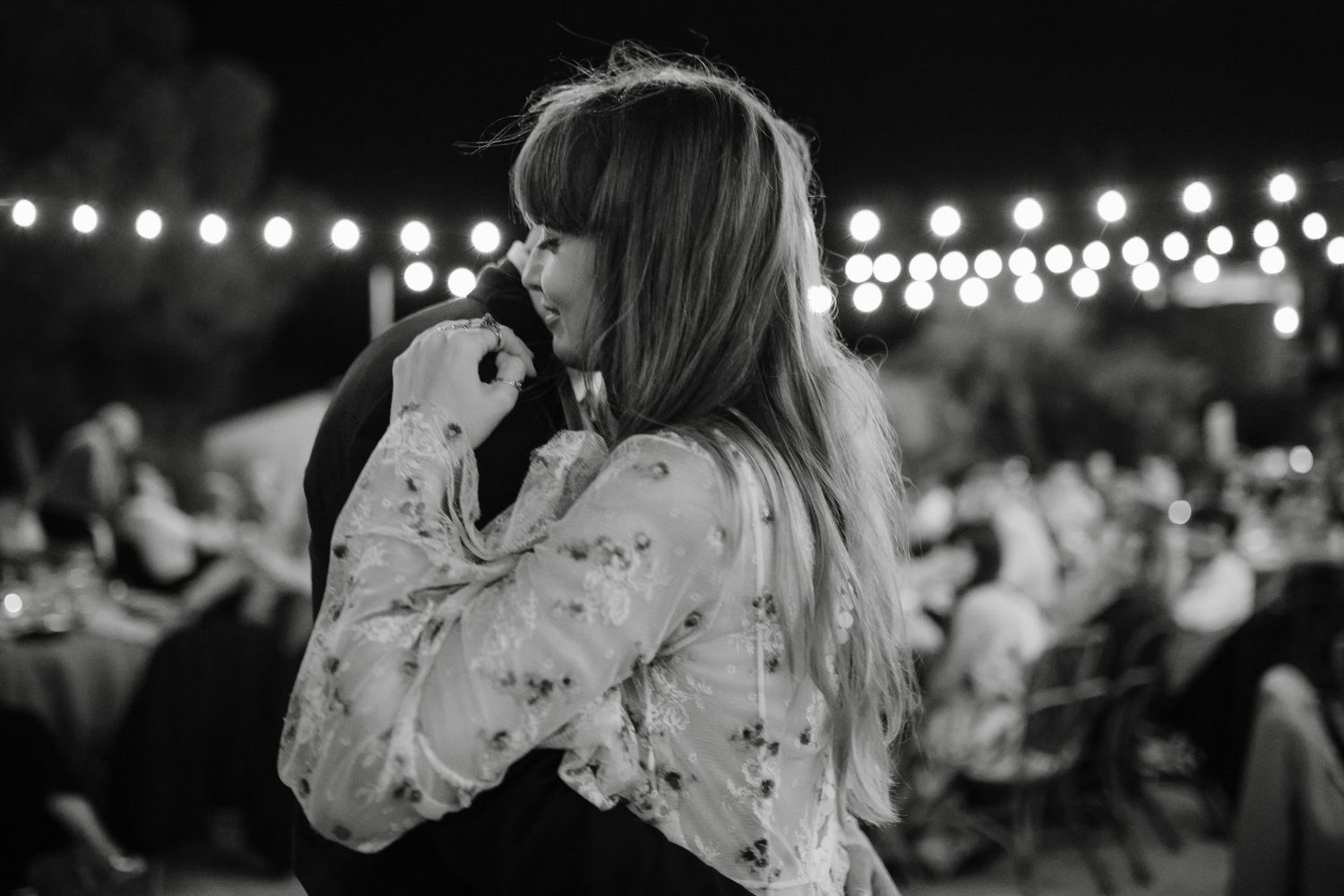 A black and white montage of people dancing at a wedding reception with string lights glowing overhead.