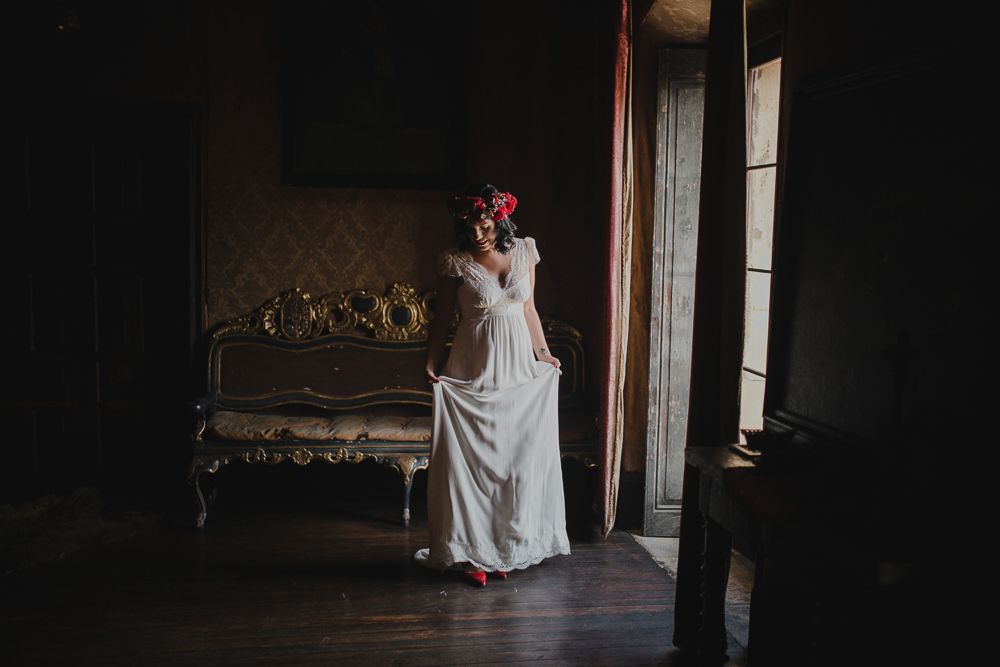 Ethereal bridal portrait in a flowing white dress against dark vintage interior.