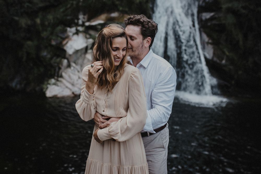 A romantic moment captured by a scenic waterfall.