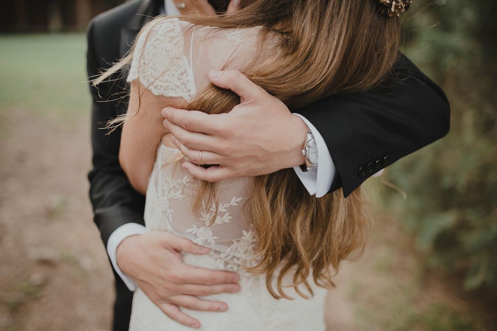 Close-up shot of romantic embrace highlighting lace wedding dress details.
