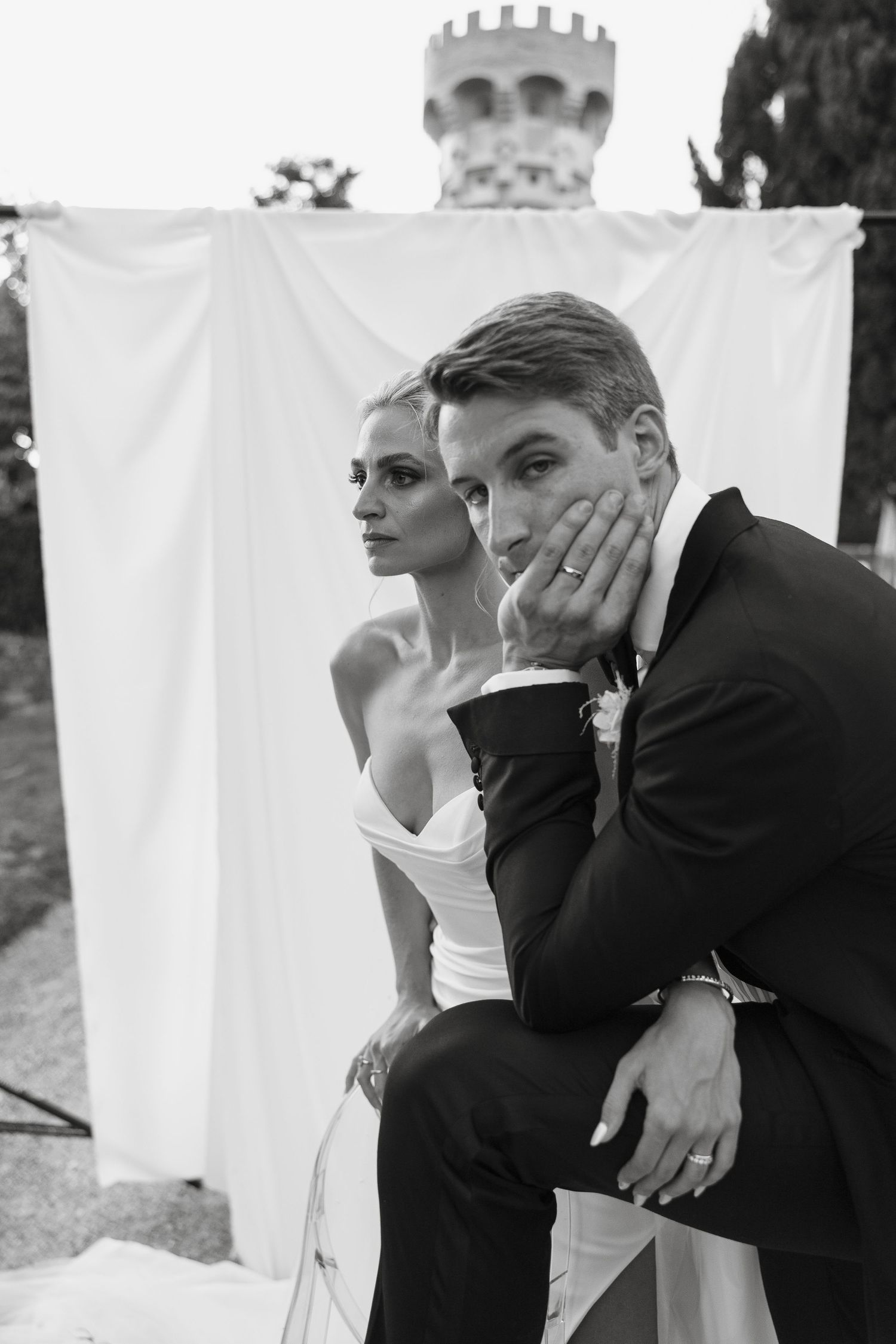 Intimate black and white wedding portrait against white backdrop with castle in background.